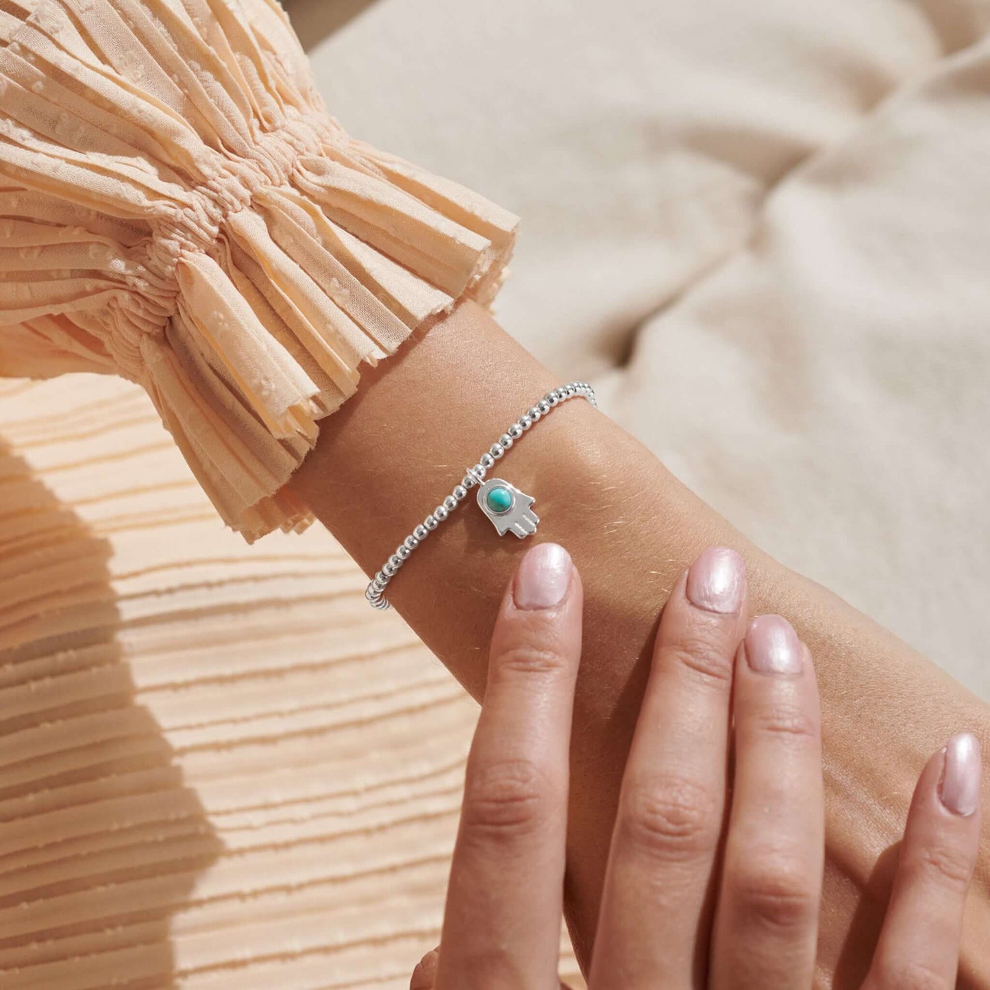 Model with silver bracelet with hamsa and turquoise stone on a card