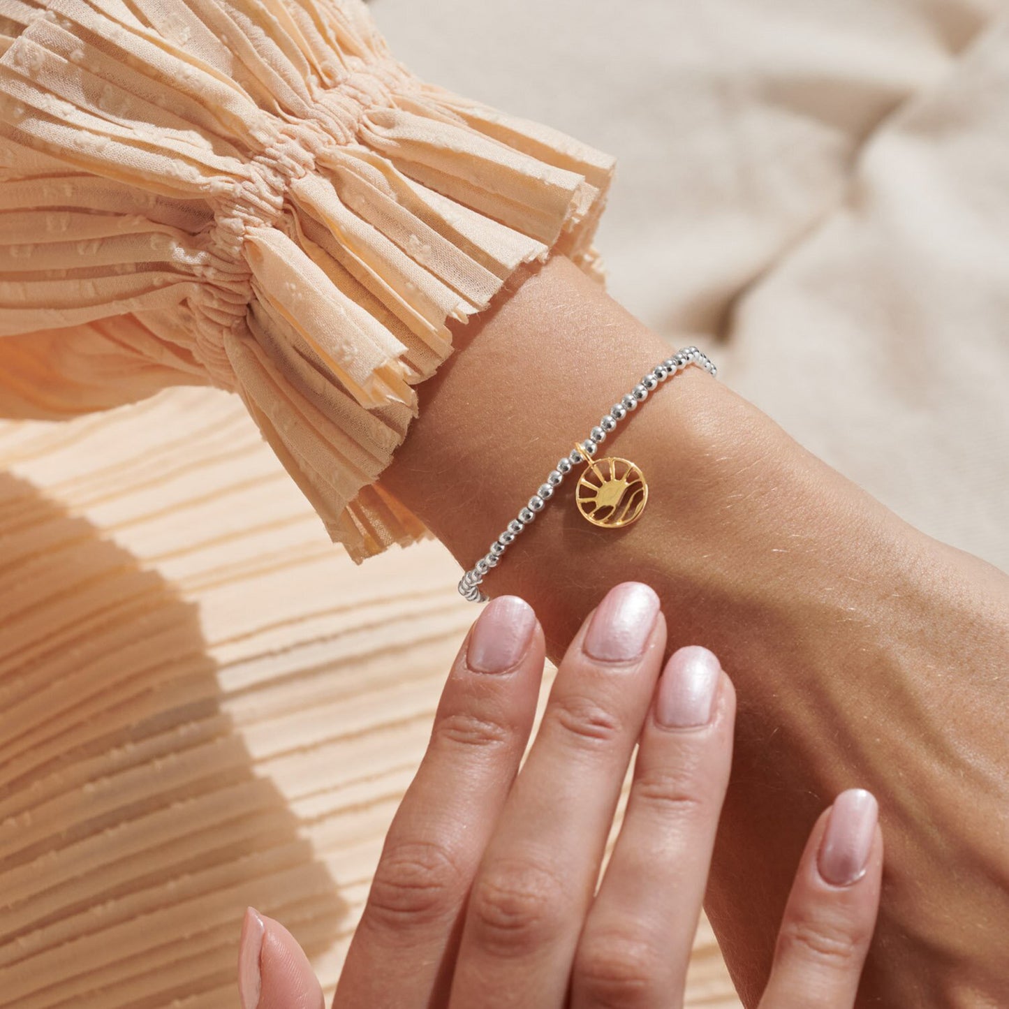 Model wearing silver and gold bracelet with sunrise charm