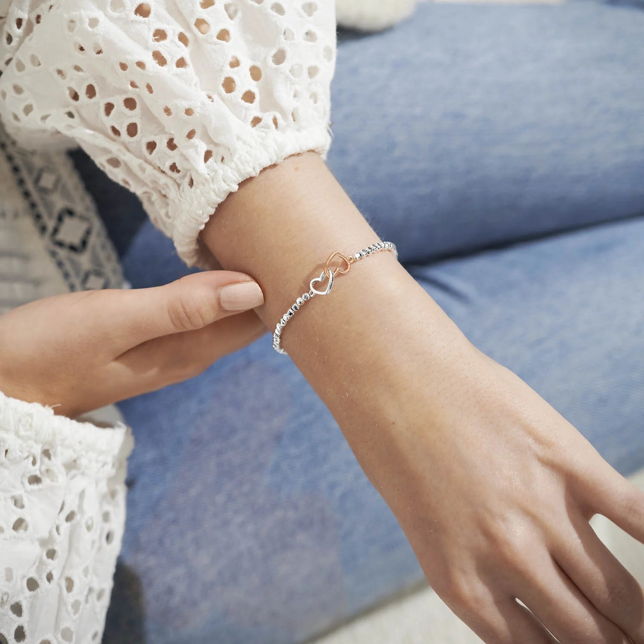Model wearing a silver beaded bracelet with rose gold and silver interlinking hearts