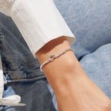 Model wearing a silver beaded bracelet with two silver hands making a heart