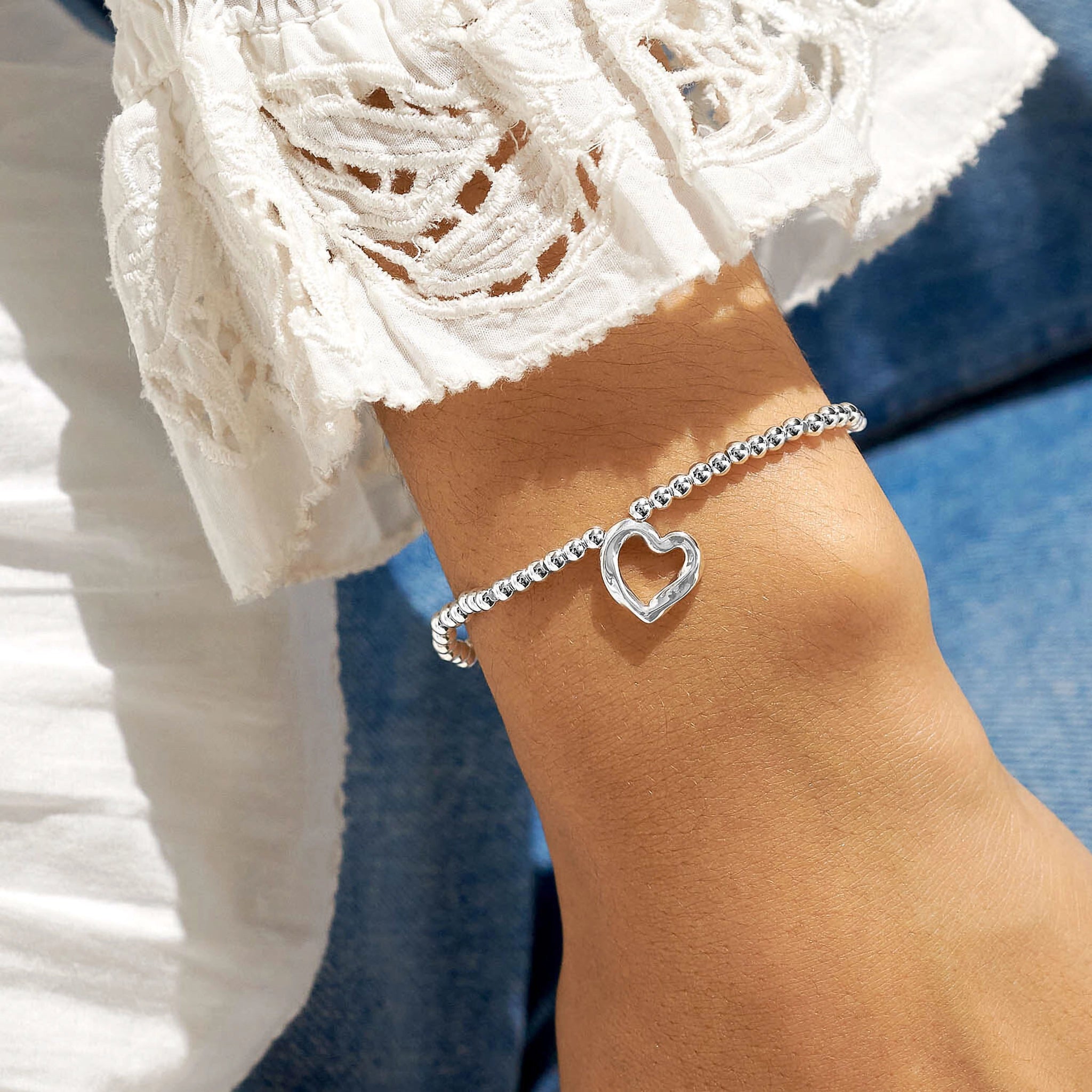 Model wearing a silver beaded bracelet with a silver wavy heart