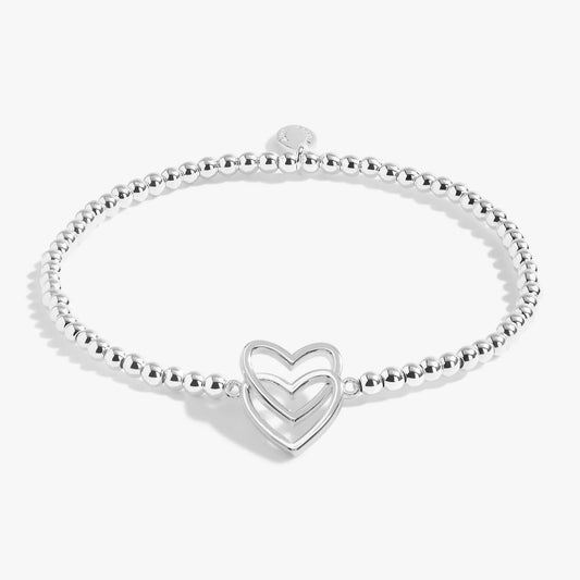A silver beaded bracelet with two stacked silver interlinking hearts 