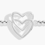 Detail of a silver beaded bracelet with two stacked silver interlinking hearts