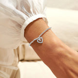 Model wearing a silver beaded bracelet with a CZ open heart charm