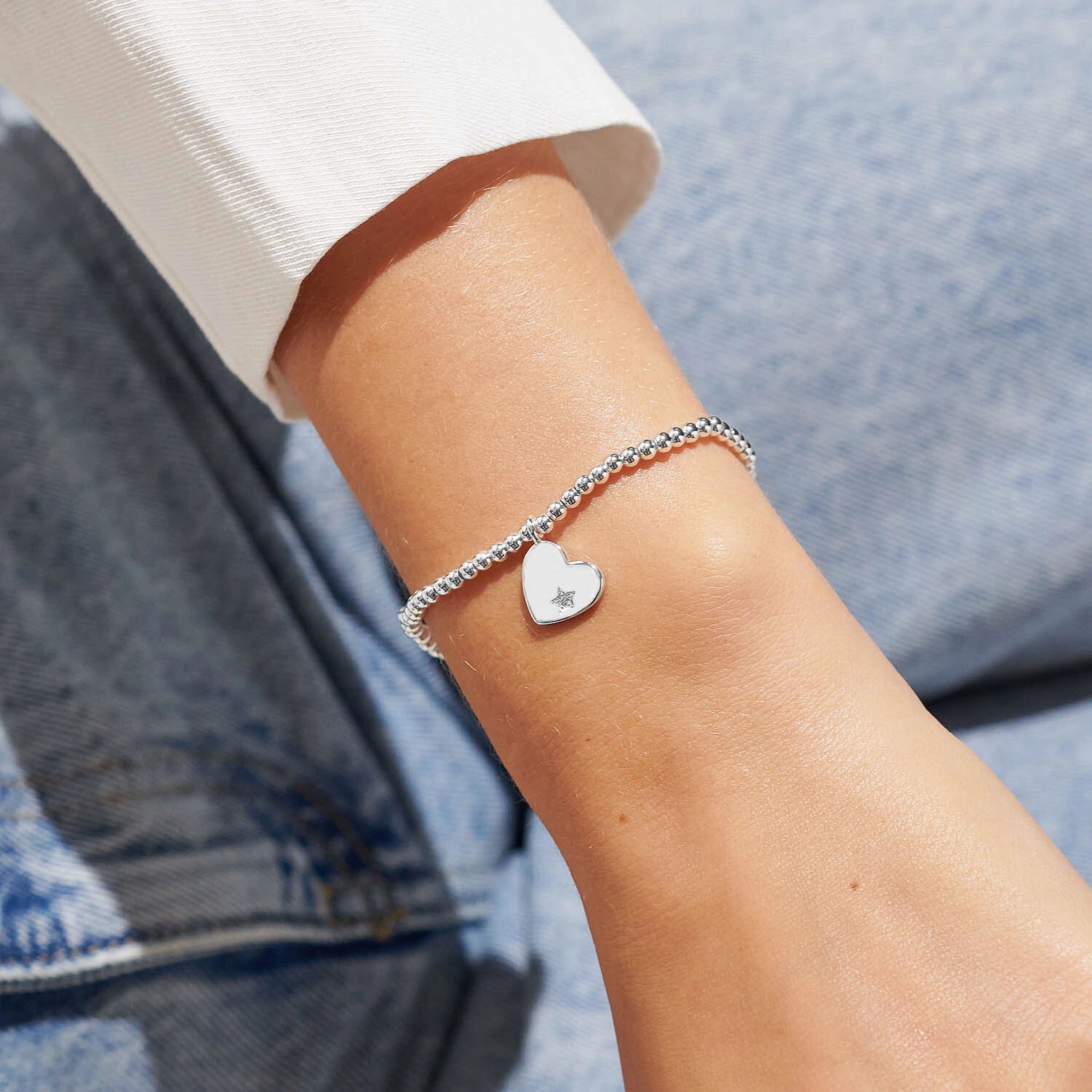 Model wearing a silver beaded bracelet with a silver heart with a CZ stone 