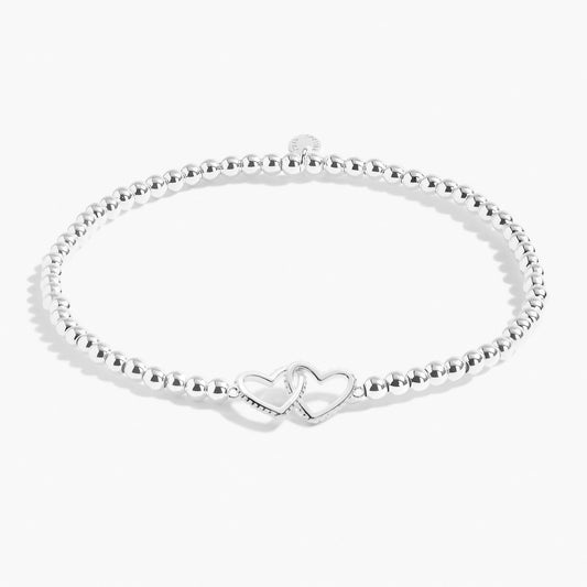A silver beaded bracelet with a two silver interlocked hearts