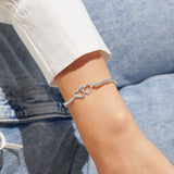 Model wearing a silver beaded bracelet with a two silver interlocked hearts
