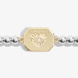 Detail of silver beaded bracelet with a gold pendant engraved with an eye in a heart with a CZ stone