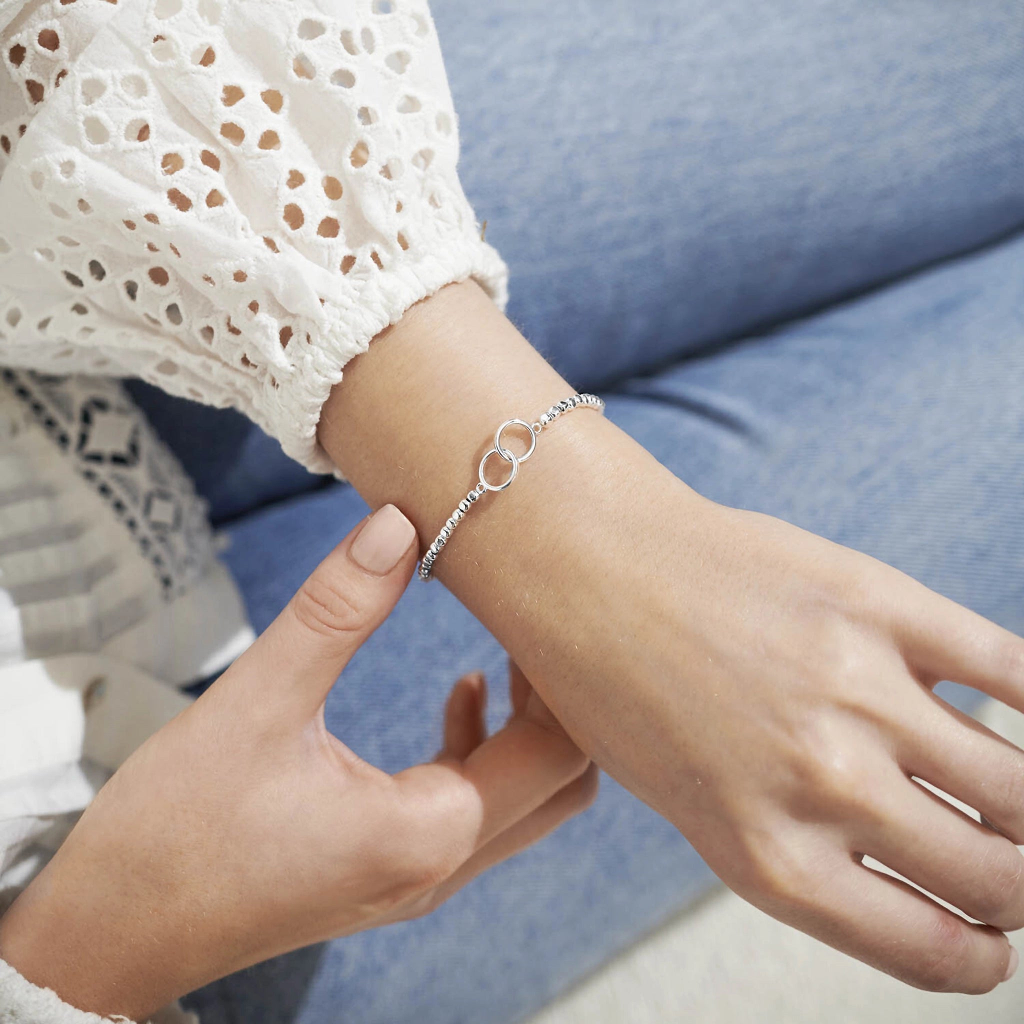 Model wearing a silver beaded bracelet with silver interlinking circles