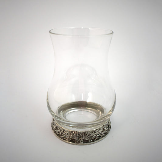 A whisky glass with a pewter base engraved with thistles