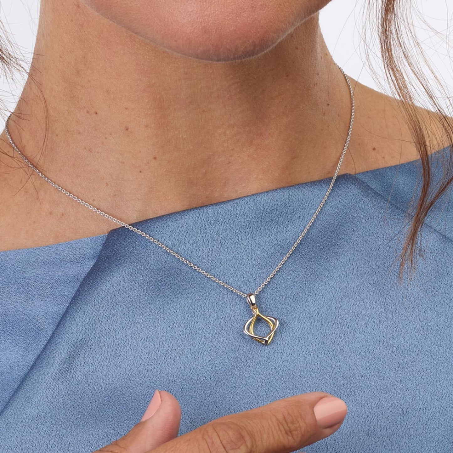 Model wearing a double silver and gold paseo shaped pendant with silver chain