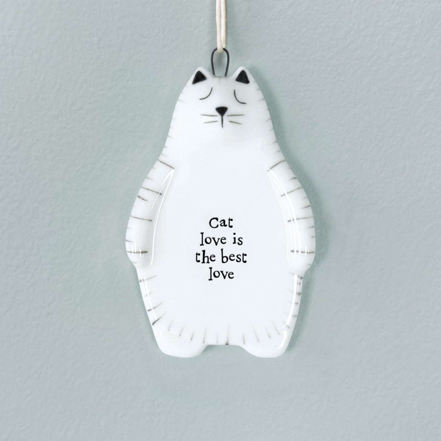 White ceramic hanger shaped like a cat with painted details and a phrase
