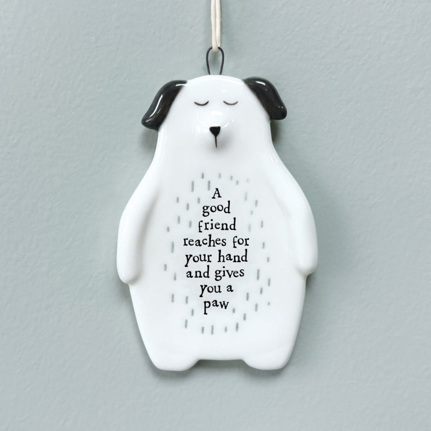 White ceramic hanger shaped like a dog with painted details and a phrase