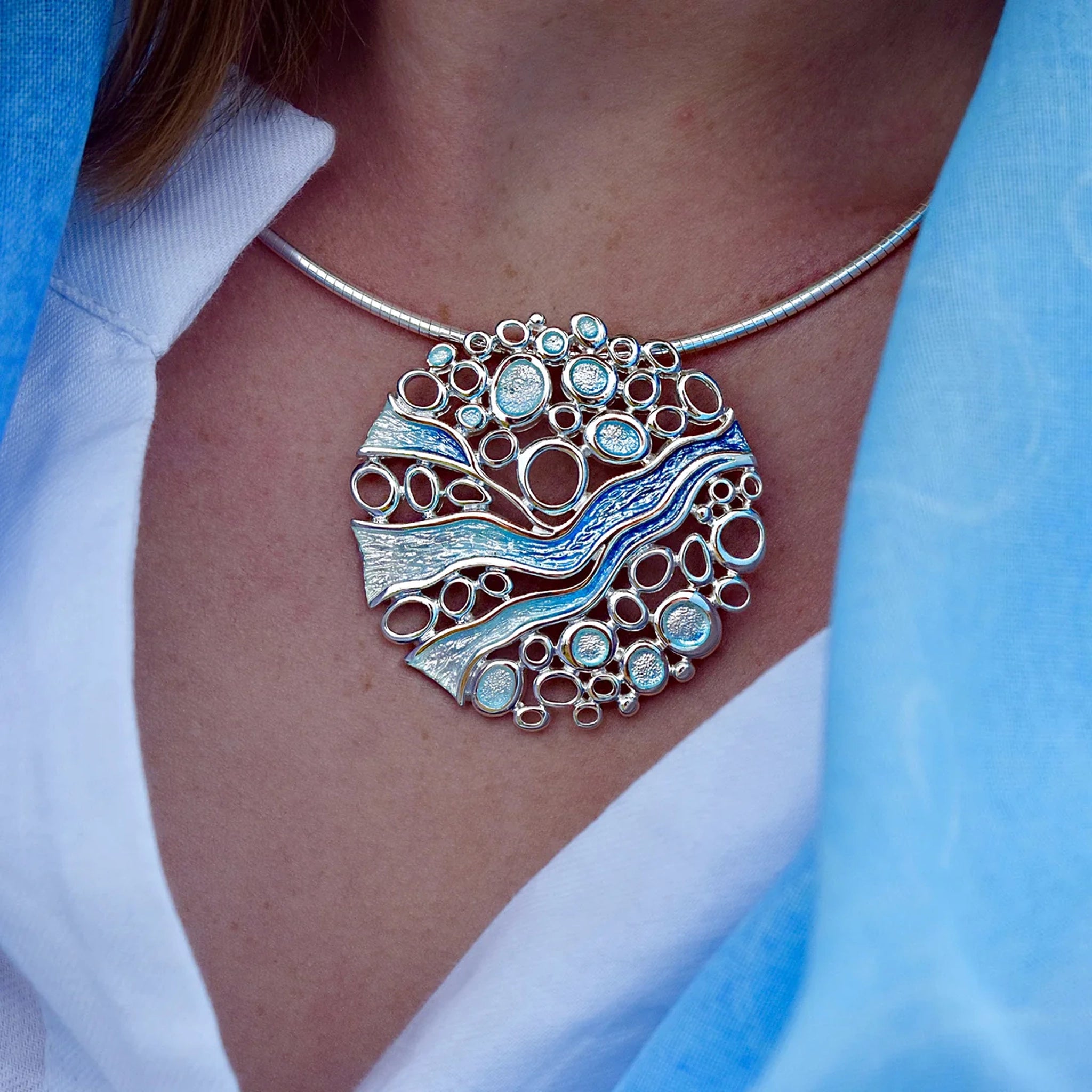Model wearing large round arctic blue enamelled pendant on a silver wire.