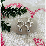 Silver earrings featuring two rings of circles and a dangling silver teardrops lifestyle image