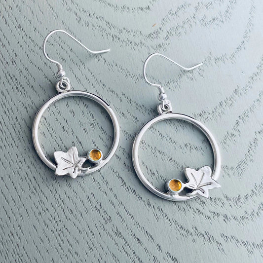 Round loop shaped silver earrings featuring autumn leaves and citrine stones