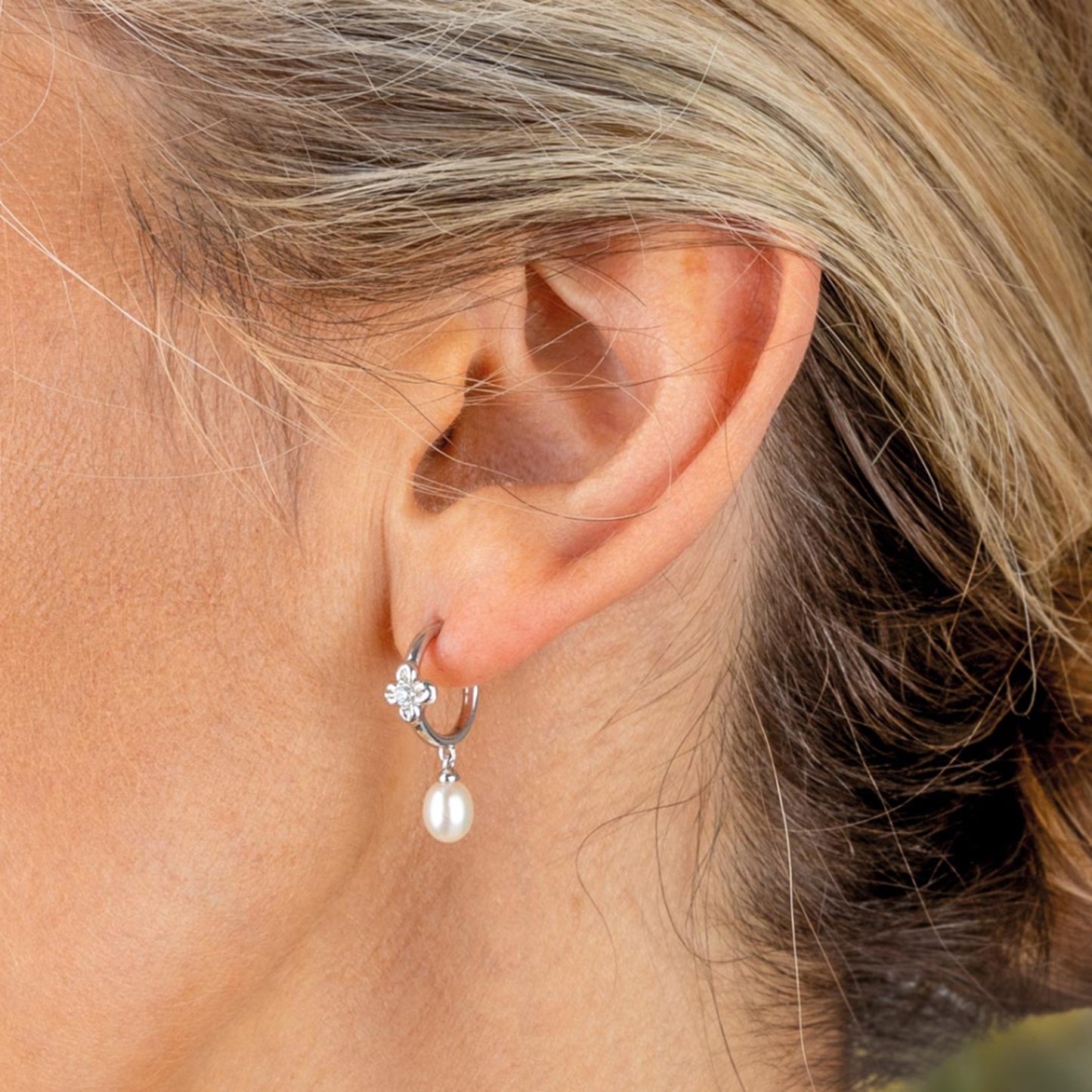 Model wearing silver hoop earrings with CZ set flower details and elegant drop freshwater pearls