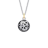 Silver coin shaped pendant with tiny flower design and oxidisation with a gold bail on a silver chain