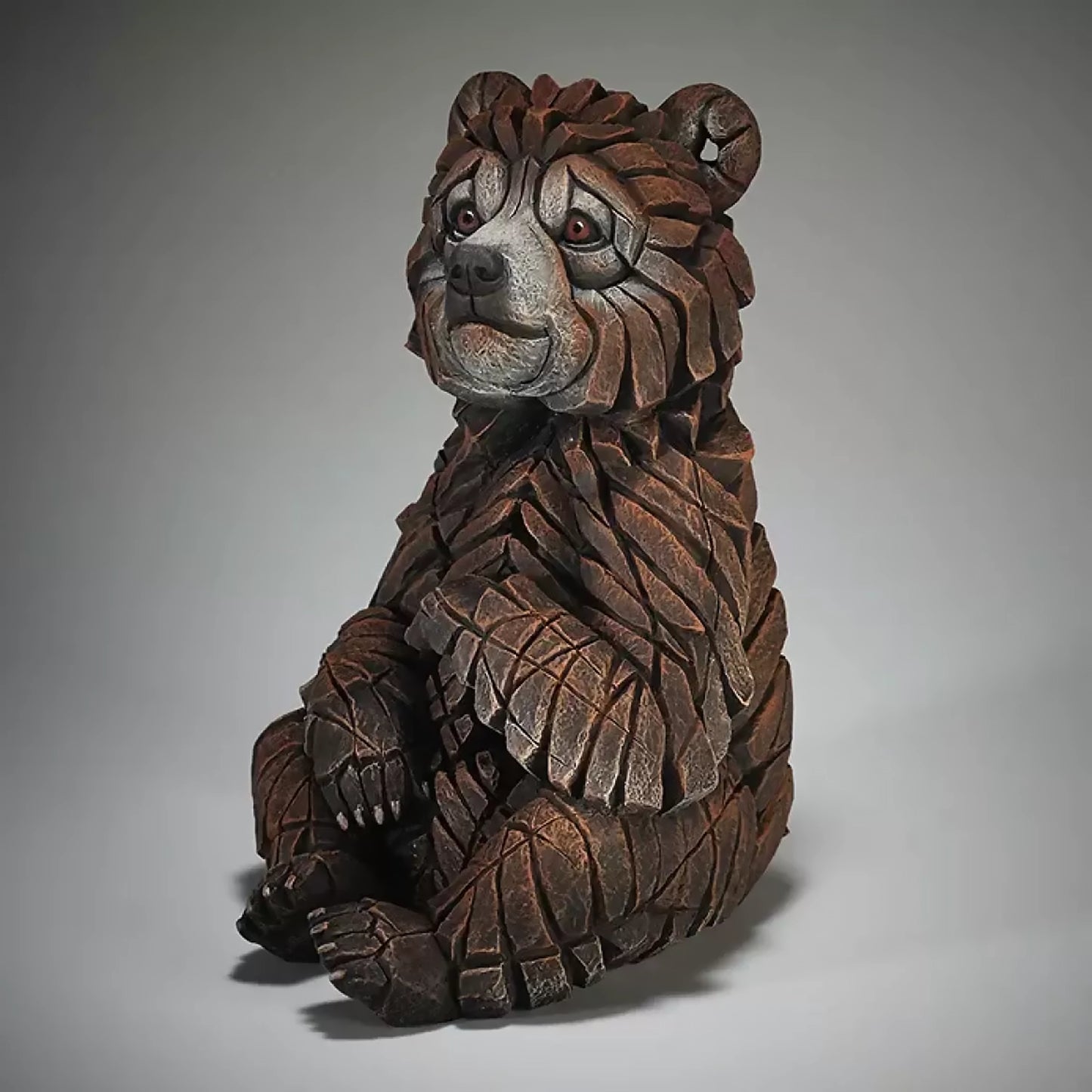 A textured and painted sitting bear cub sculpture