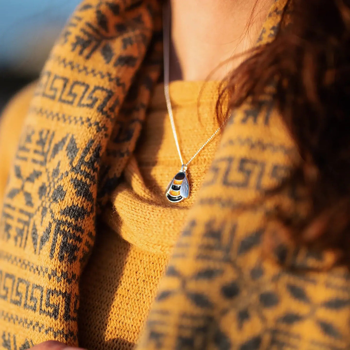 Model wearing polished silver bee pendant in black & yellow enamel on silver chain