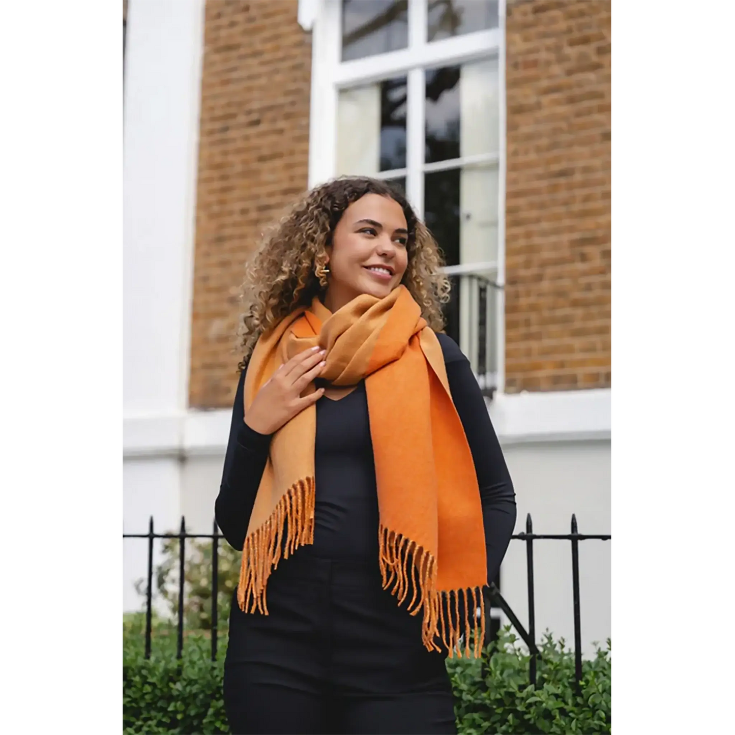 Model wearing two toned orange colour block scarf with tassel trim
