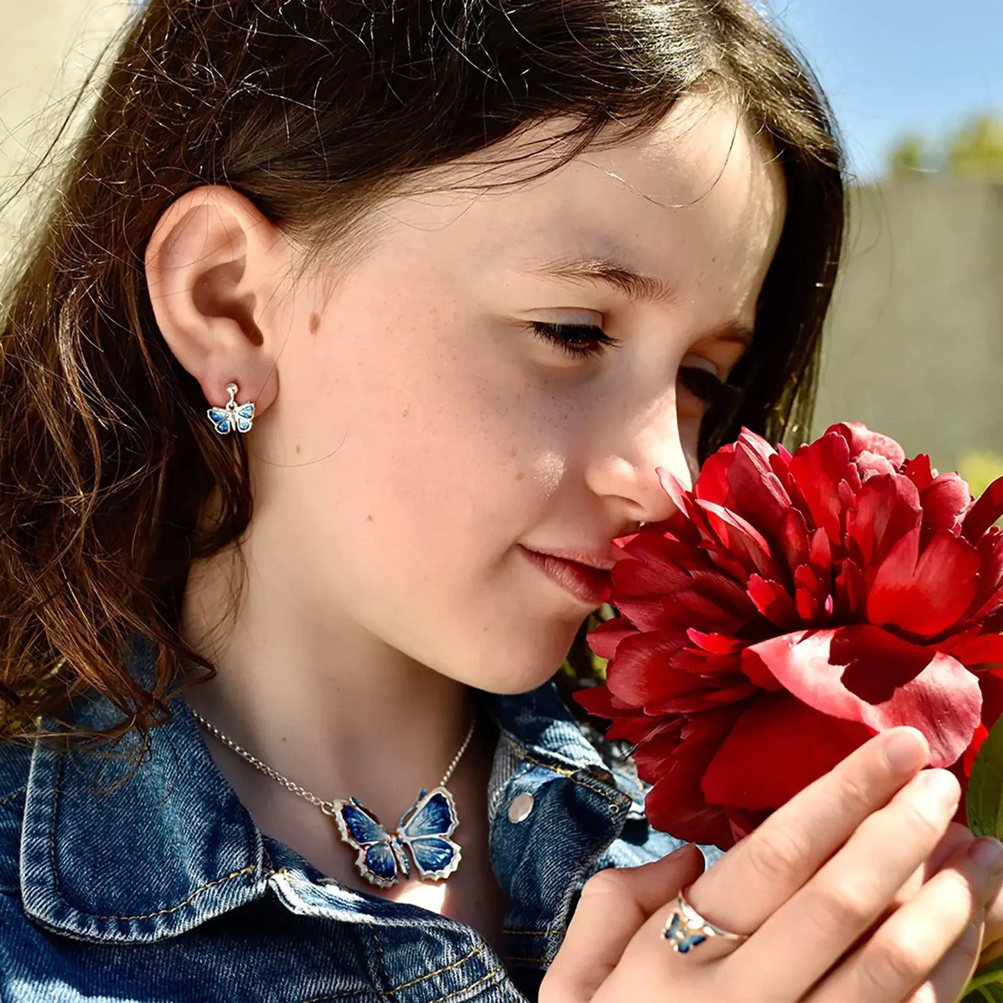 Small silver drop butterfly earrings with a blue enamel and stud posts on model