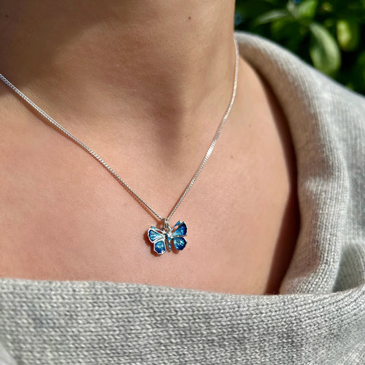 Polished silver butterfly pendant in blue enamel with silver chain on model