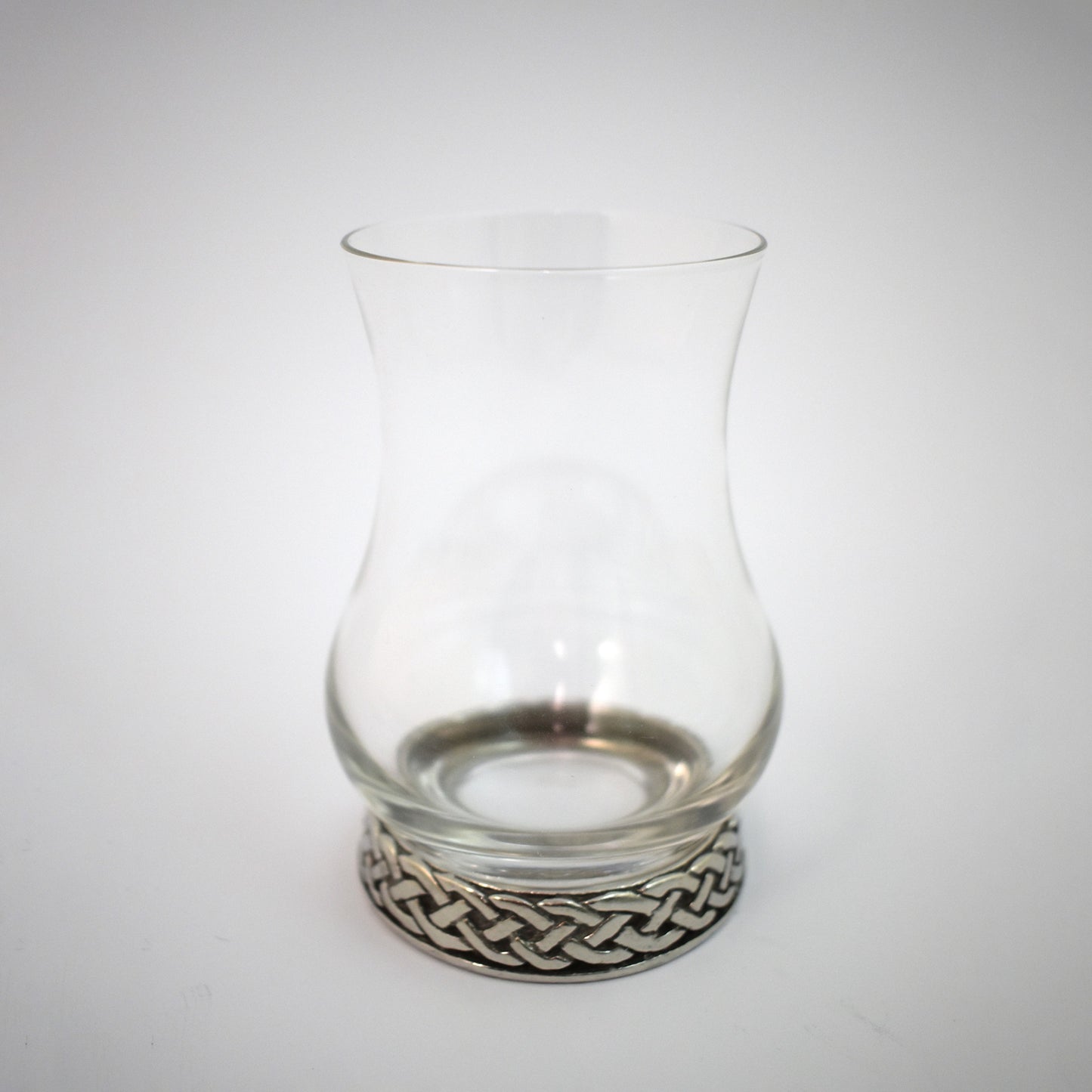 A whisky glass with pewter base engraved with a celtic knot