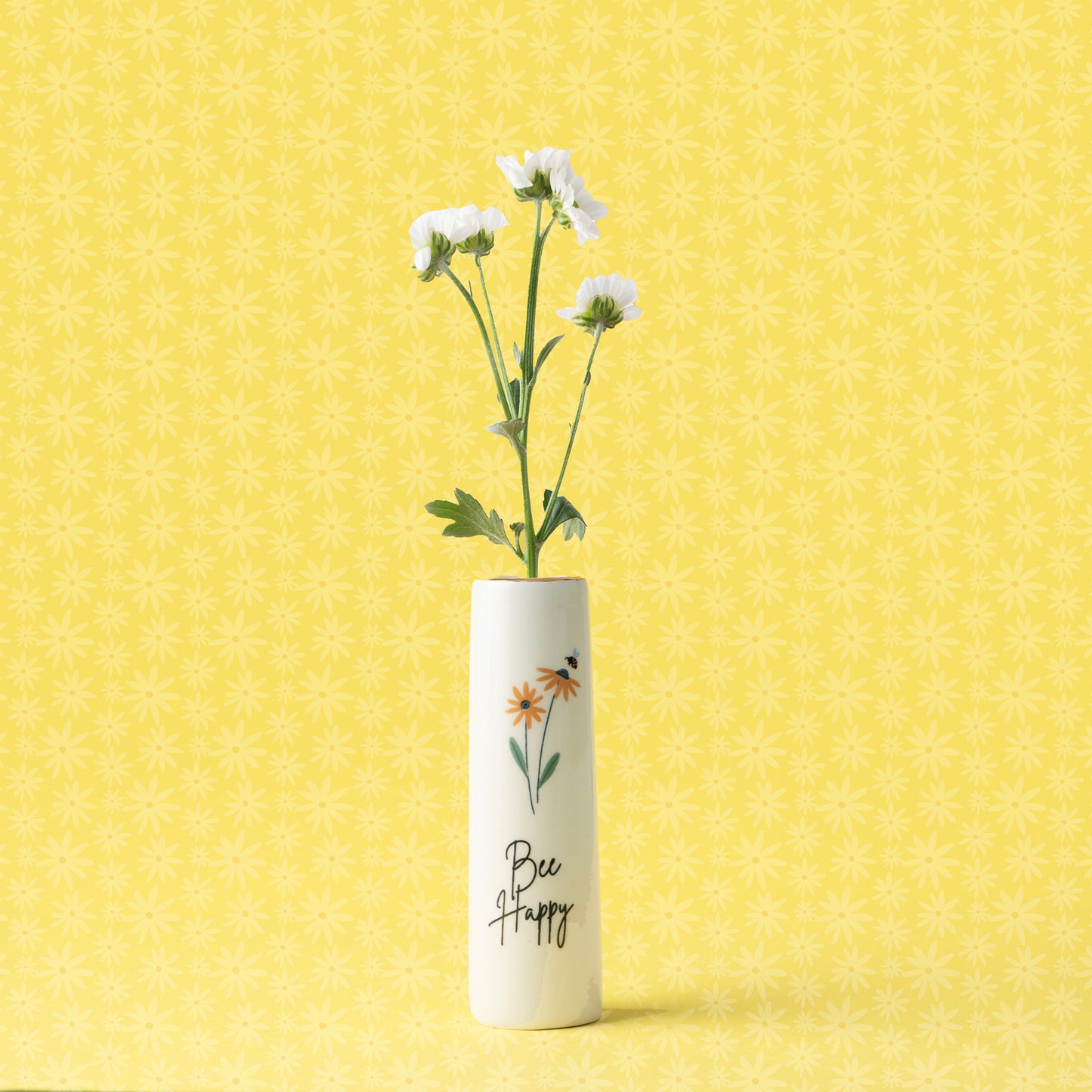 A ceramic bud vase featuring florals and the words 'bee happy'