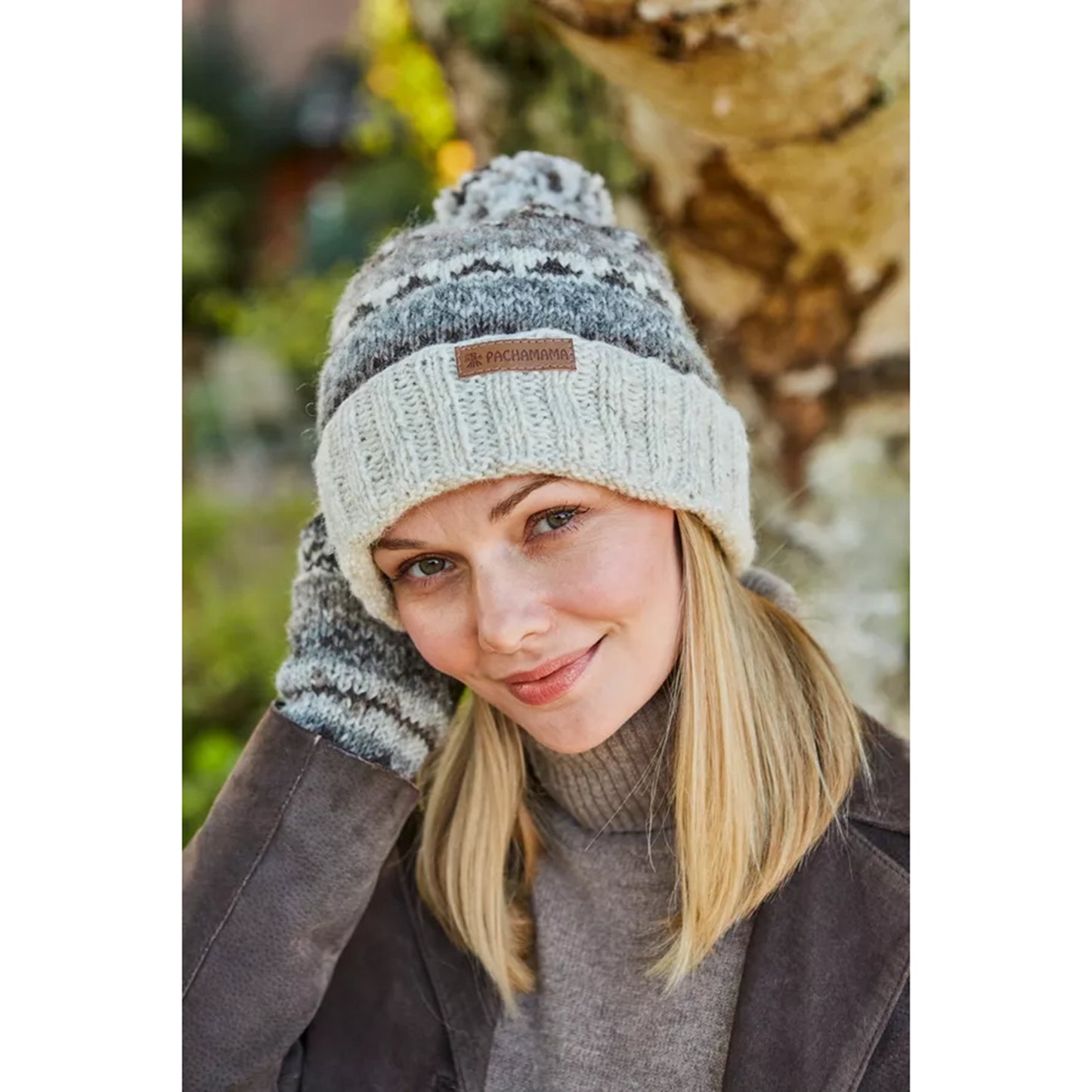 Model wearing a natural colour knitted bobble hat with fairisle pattern and roll up