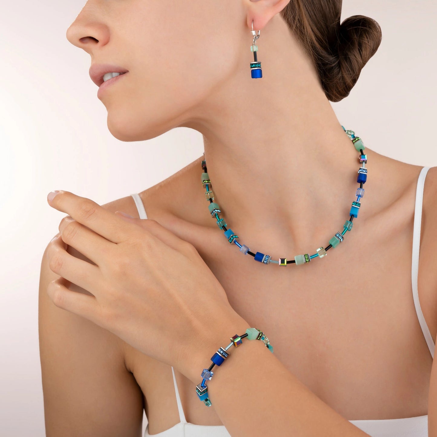 Model wearing a set of jewellery with a variety of cube shaped stones in blue and green colours