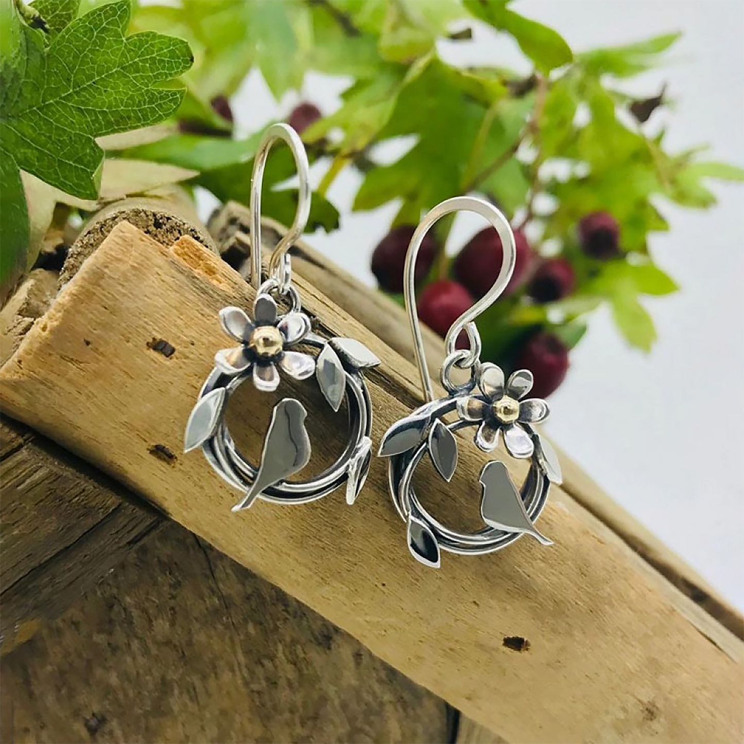 Posed round silver bird nest earrings with bird & leaf design and a flower with a gold centre on hook fittings