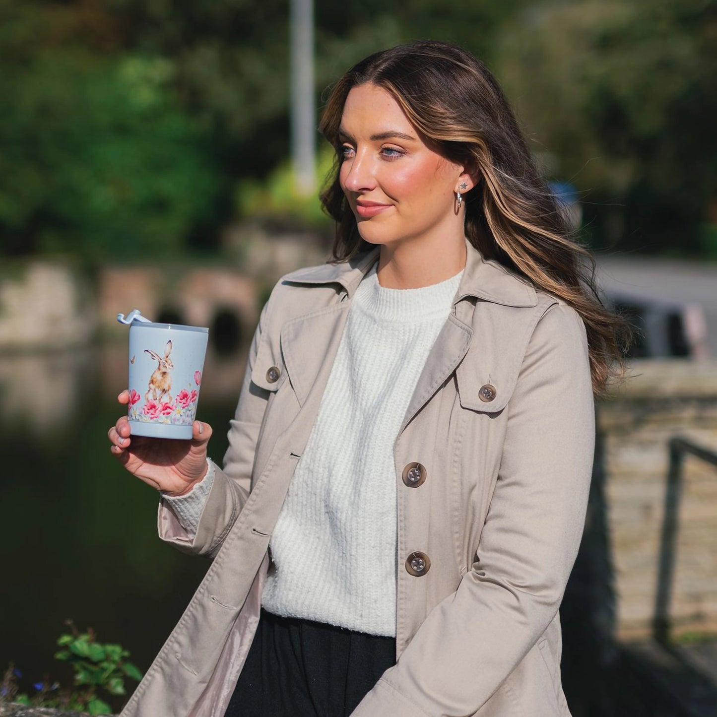 Model holding a travel cup with a hare in flowers design in a light blue
