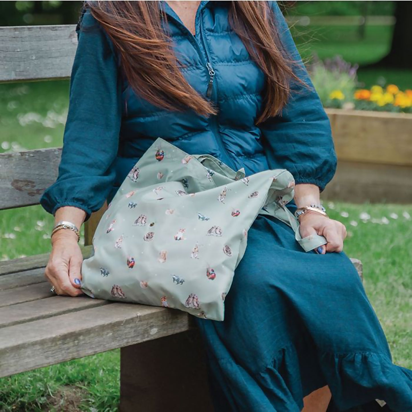 Model wearing green shopping tote bag with woodland animal repeat print