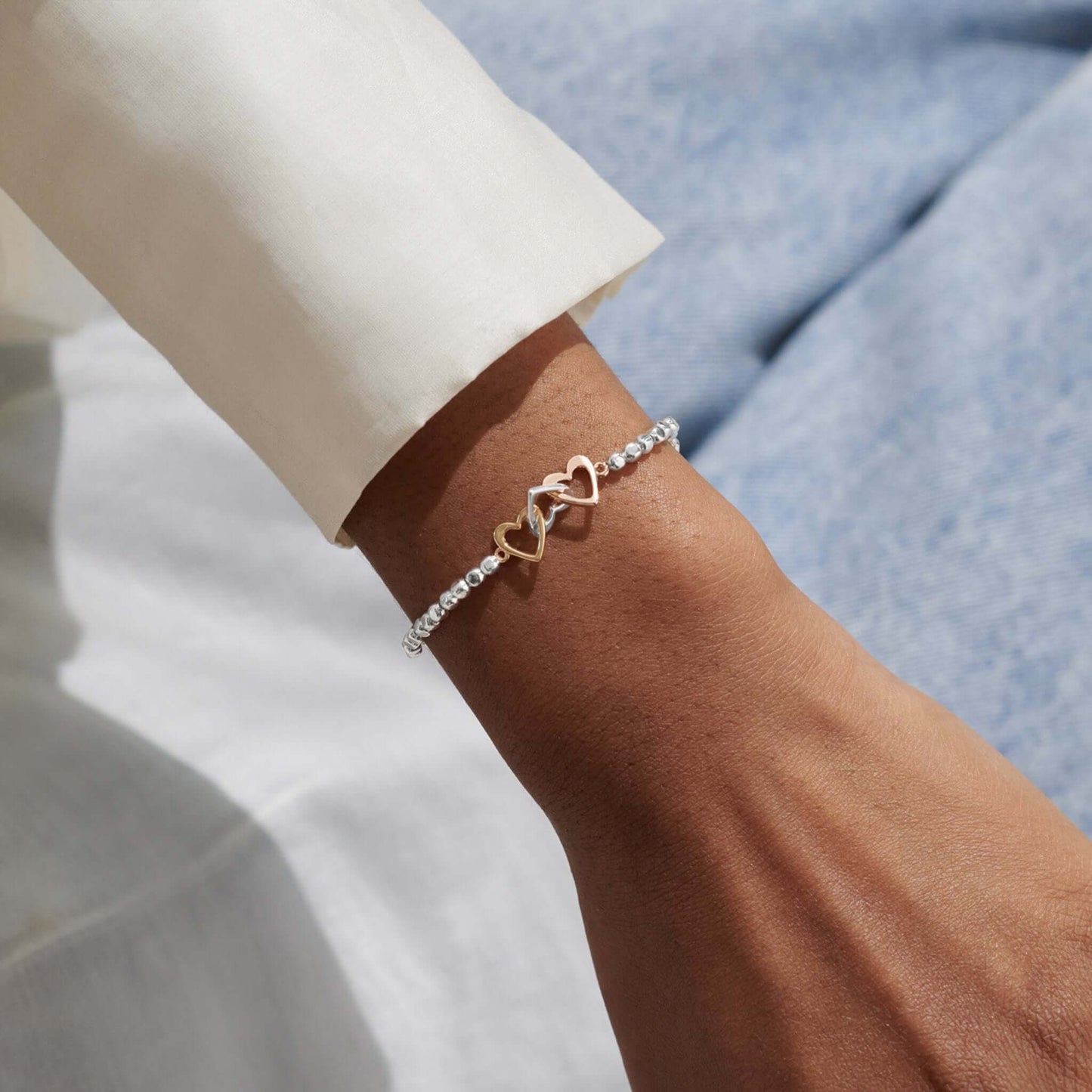 Model with silver bracelet with three interlinked hearts in silver and two toned gold