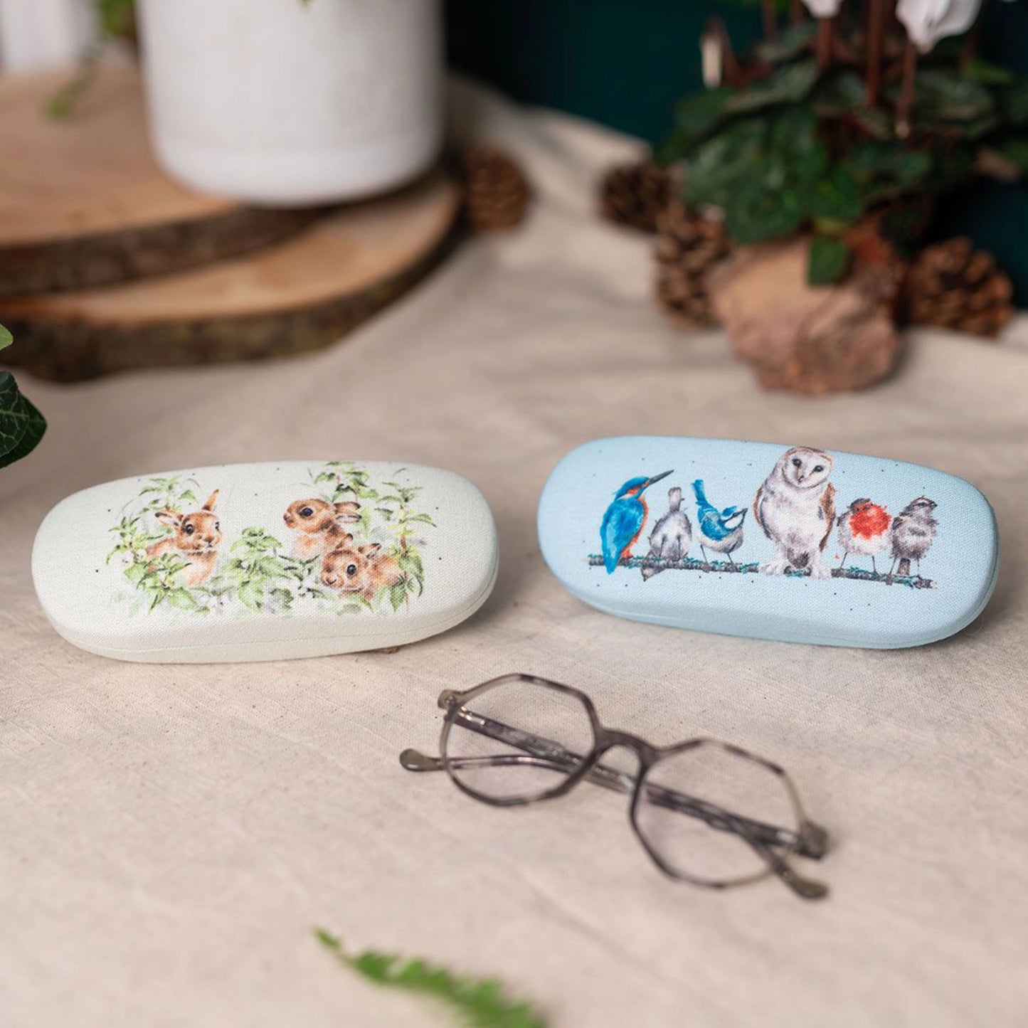 Blue and green canvas glasses cases with printed row of birds and hares illustrations