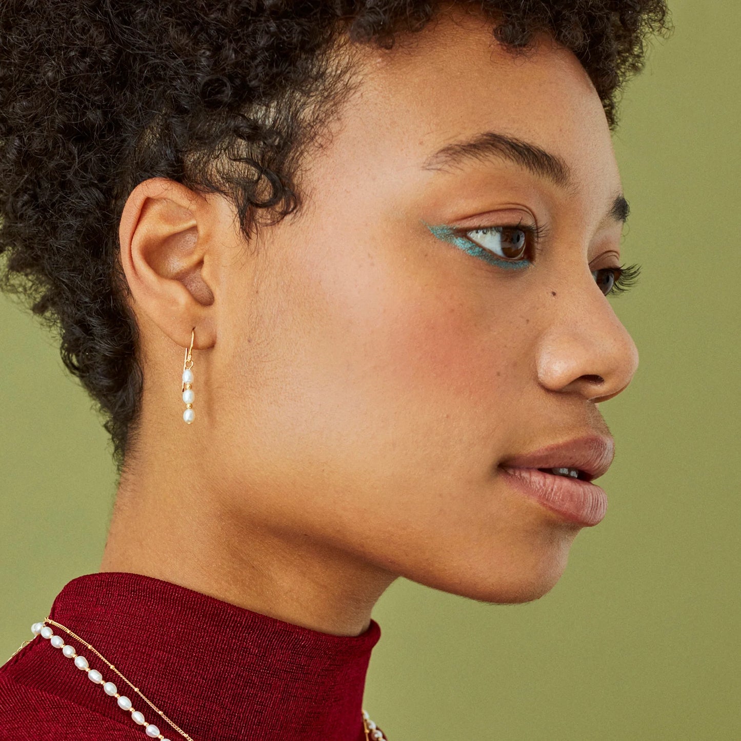 Model wearing a pair of seed pearl drop earrings with gold spacers and hooks in 18k vermeil