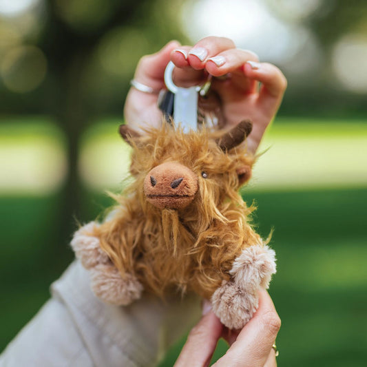 Model holding a plush Highland cow keychain