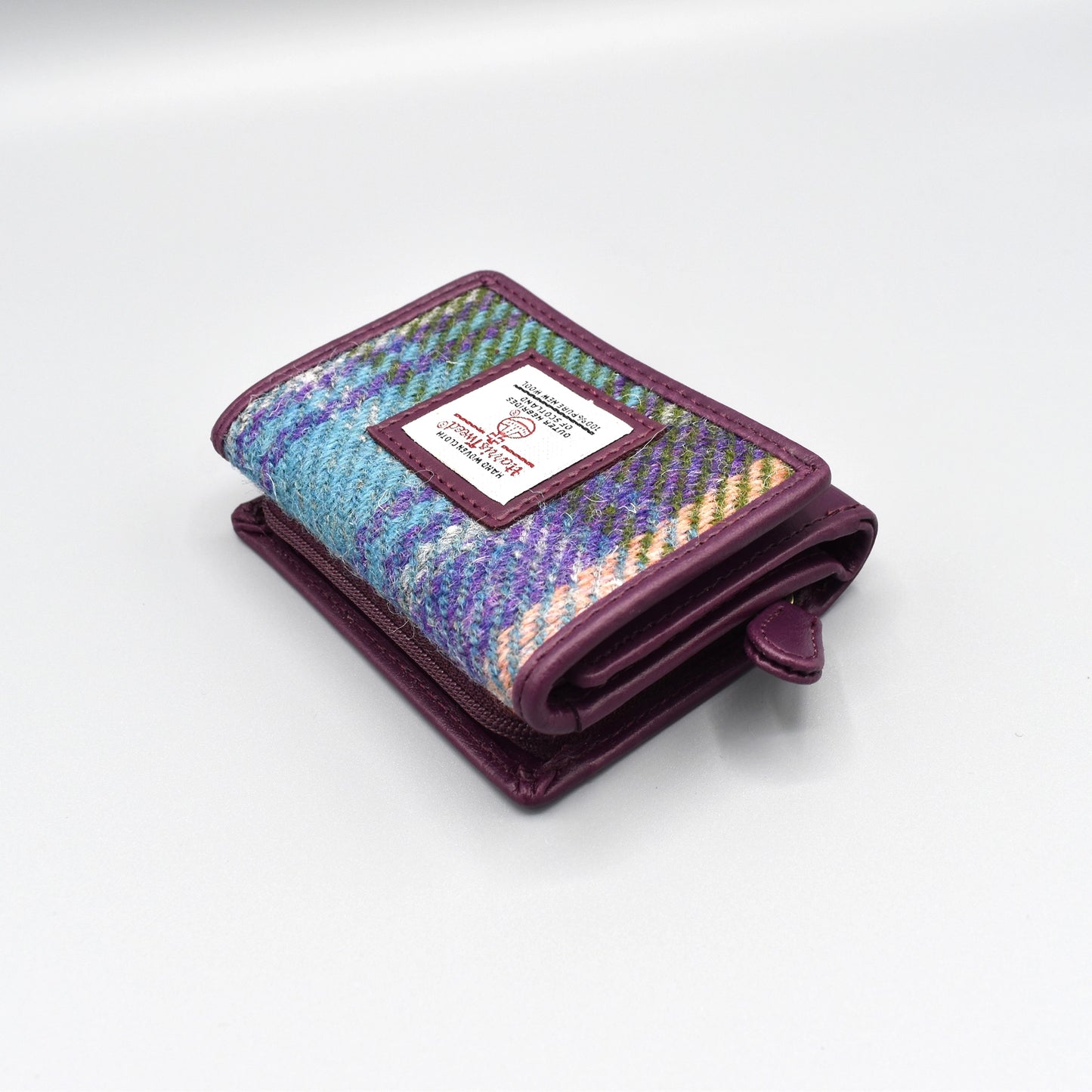A purple faux leather purse with genuine Harris Tweed plaid in the front with zip