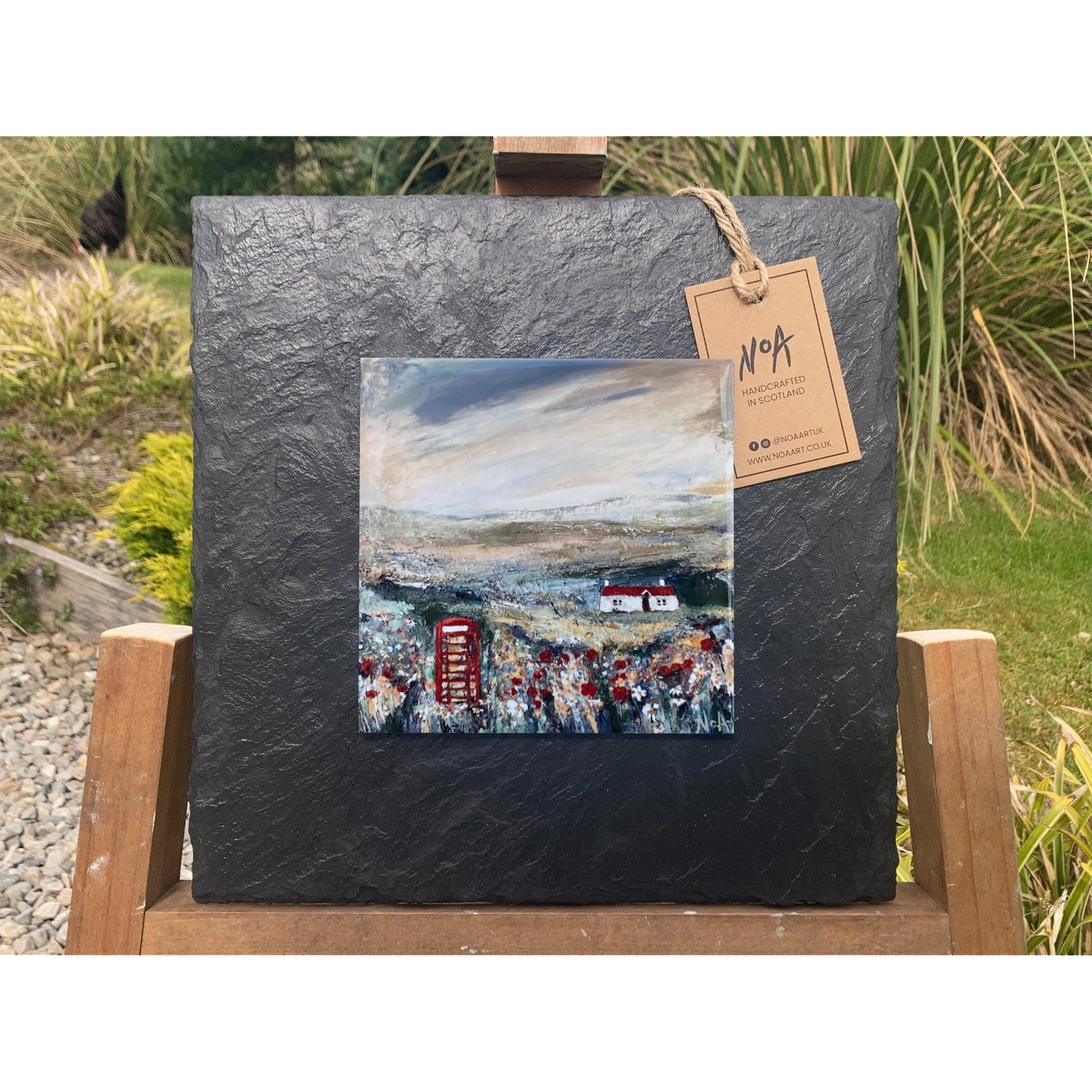 A tile mounted on slate featuring a textured painting of a bothie and telephone box
