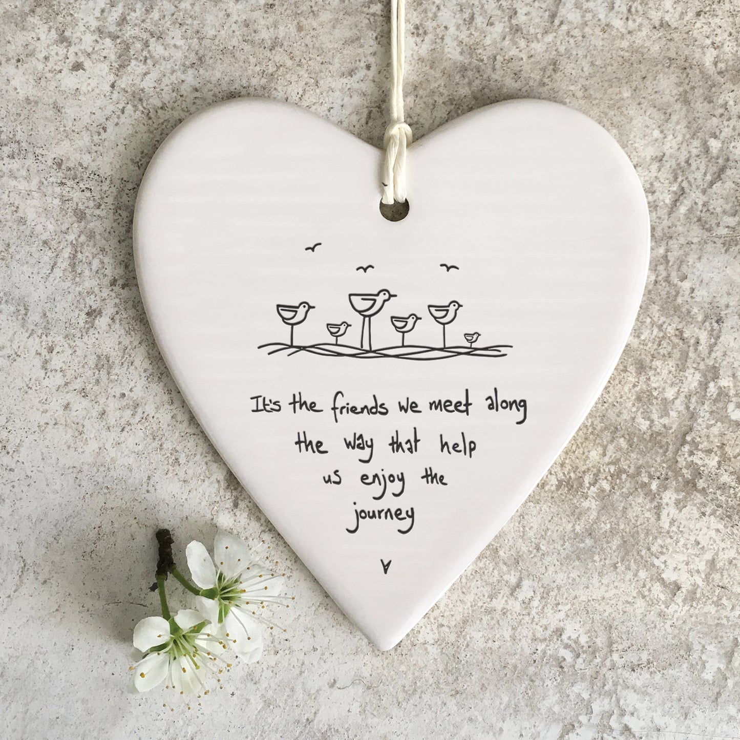 White ceramic heart with a bird illustration and a quote