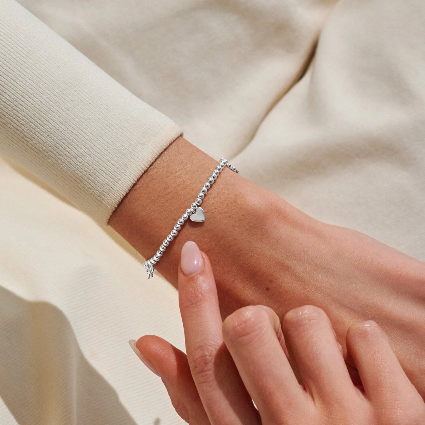 Model wearing silver beaded stretch bracelet with heart charm