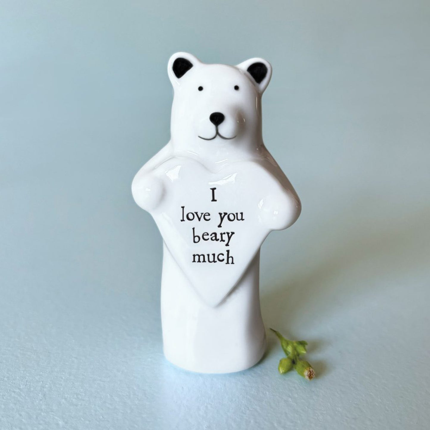 A bear figure holding a heart plaque with the words 'I love you beary much'