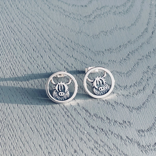 A pair of silver stud earrings featuring Highland cows in round frames