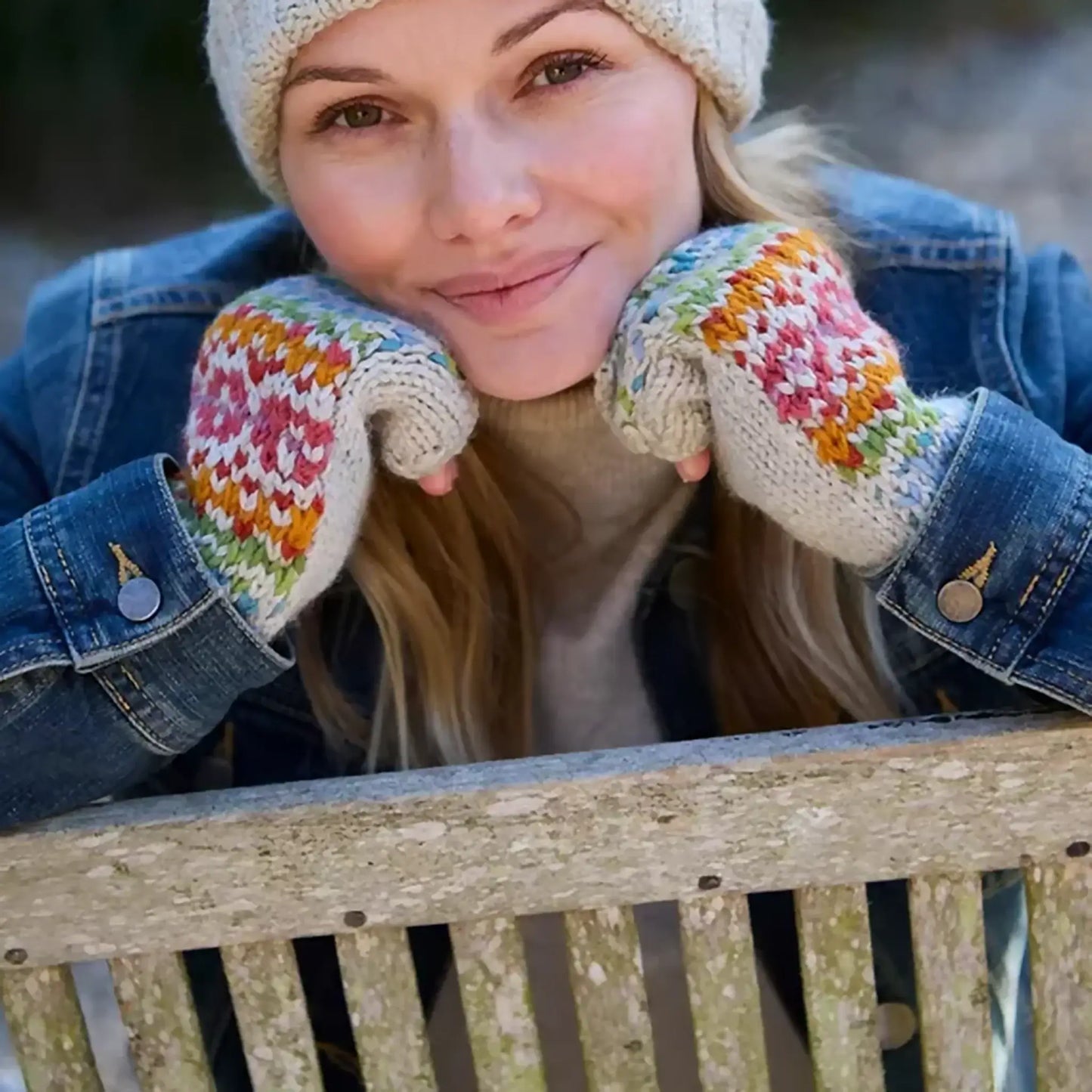 Model wearing knitted oatmeal handwarmers with rainbow chevron heart fair isle pattern