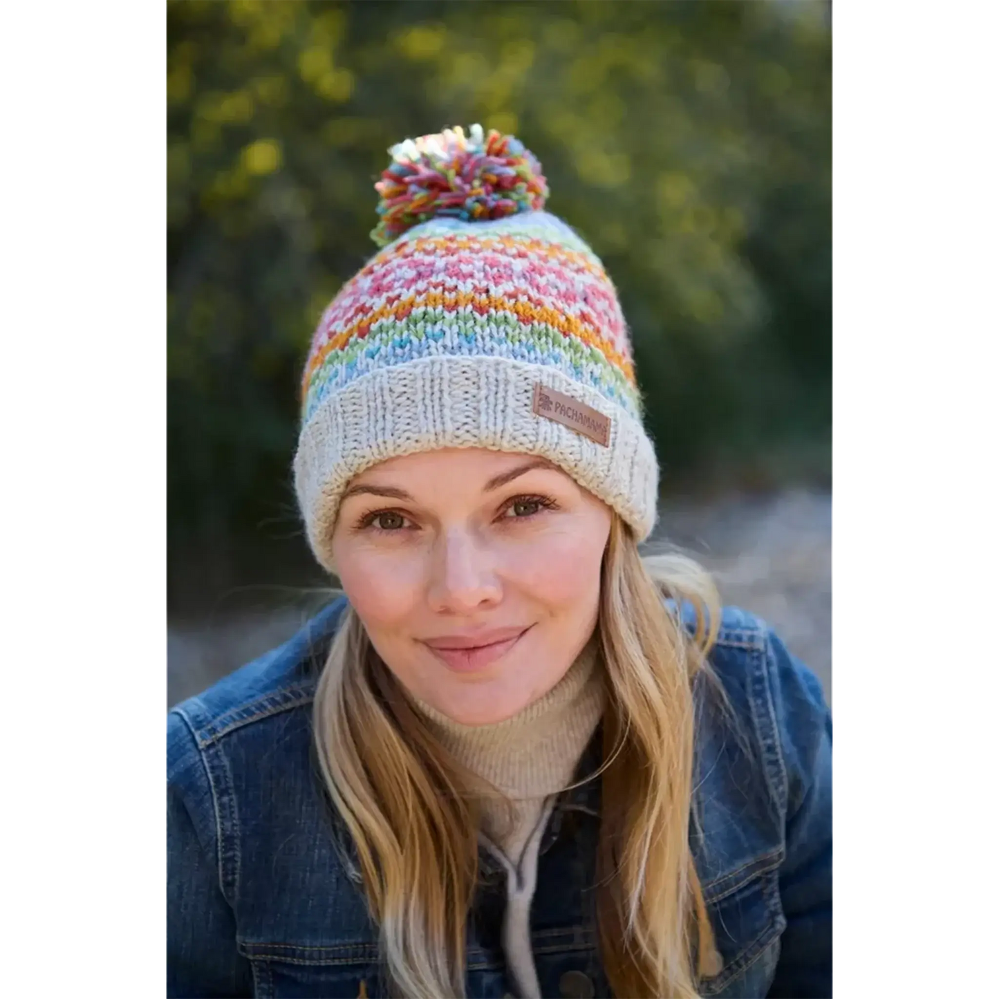 Model wearing knitted oatmeal hat with rainbow chevron heart fair isle pattern and pompom