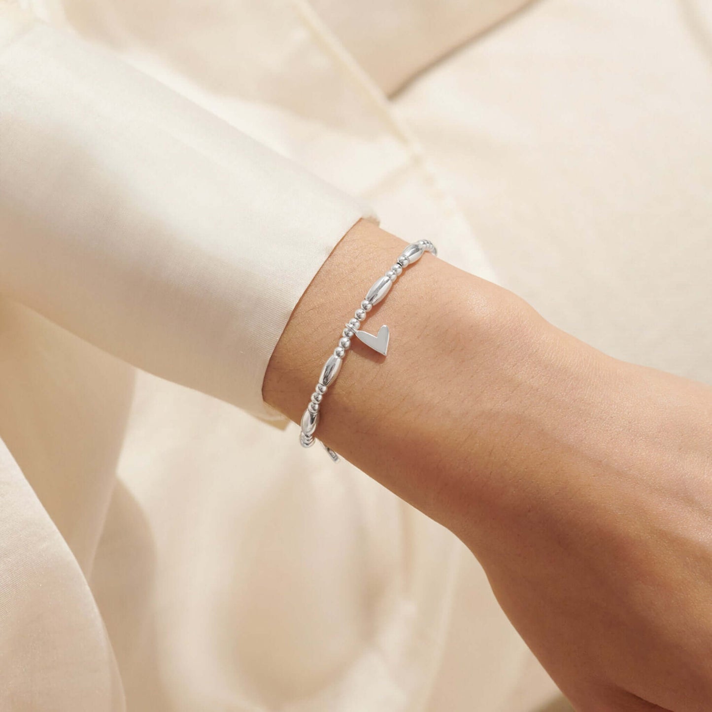 Model wearing a beaded stretch silver bracelet with three different heart charms