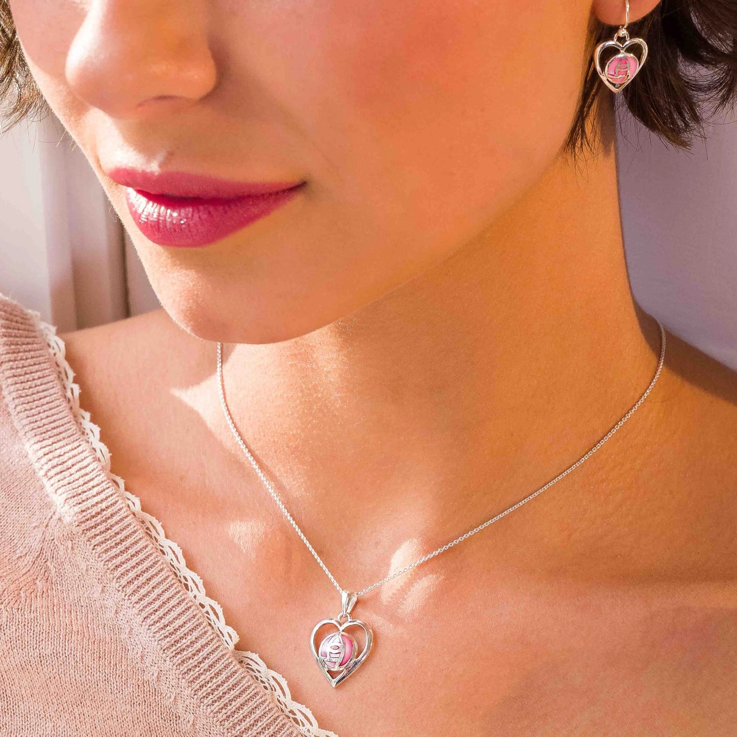 Model wearing a matching pendant and earrings set of silver heart Mackintosh rose jewellery