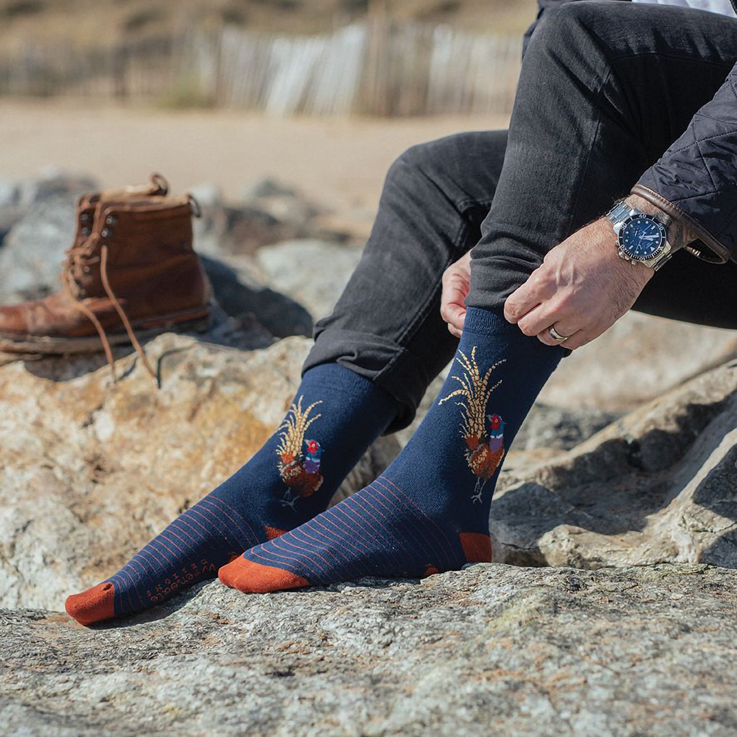 Model wearing a pair of navy blue socks with burnt orange heels and stipes with a pheasant picture