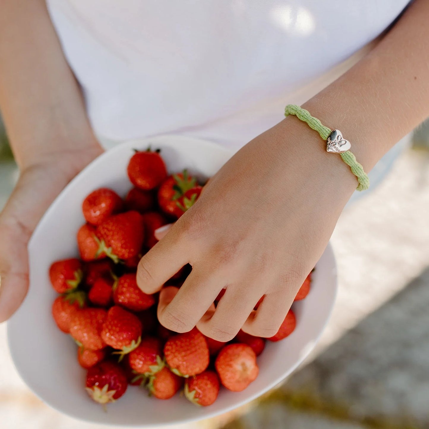 Model wearing apple green coloured bubble shaped hair tie with gold heart charm as bangle